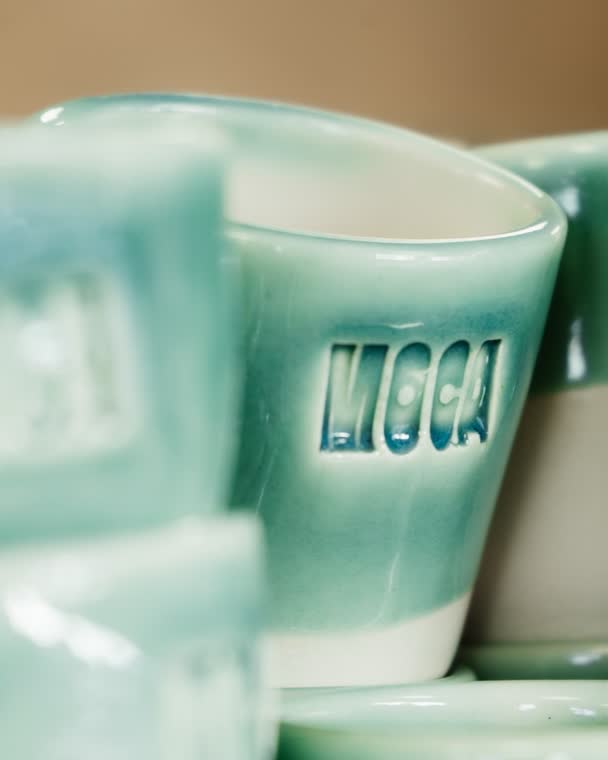 Tazas de ceramica verde apiladas con el sello MOCA