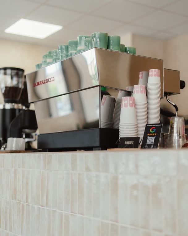 Vasos verdes y rosas sobre la maquina de espresso en la barra