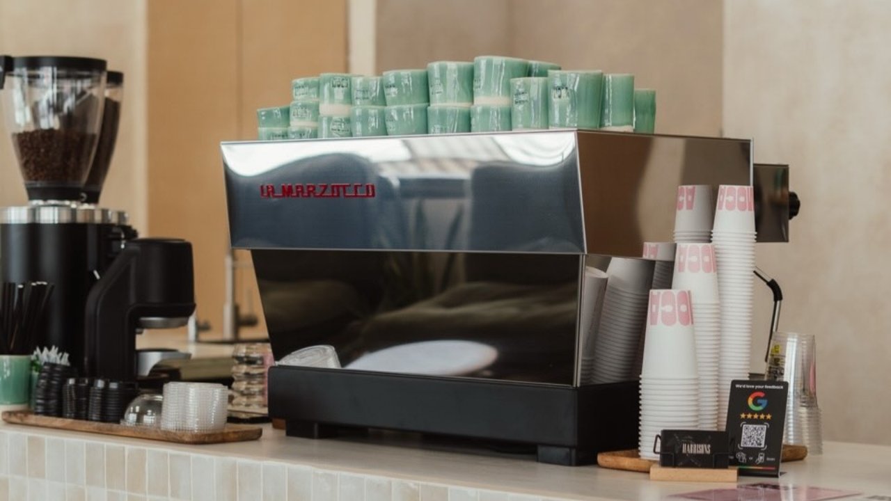 La maquina de espresso La Marzocco sobre la barra de azulejos de Moca, con tazas y molinillo