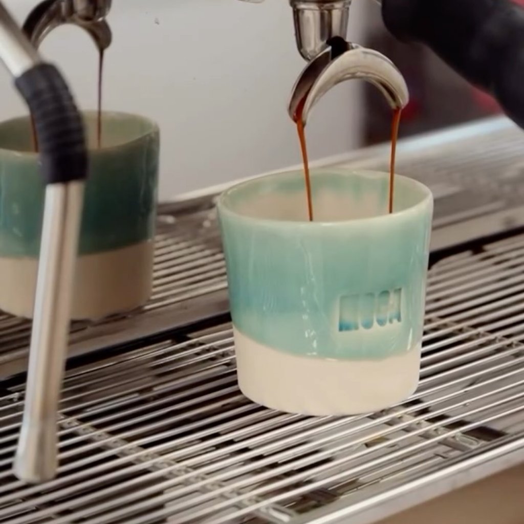 Espresso recien hecho cayendo de la maquina La Marzocco en taza de ceramica verde
